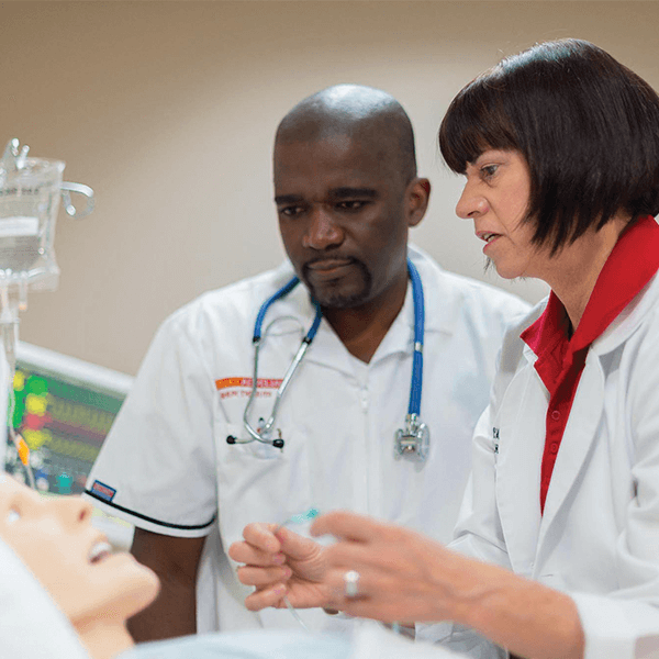 Male Nursing Student with Female Instructor in hospital room